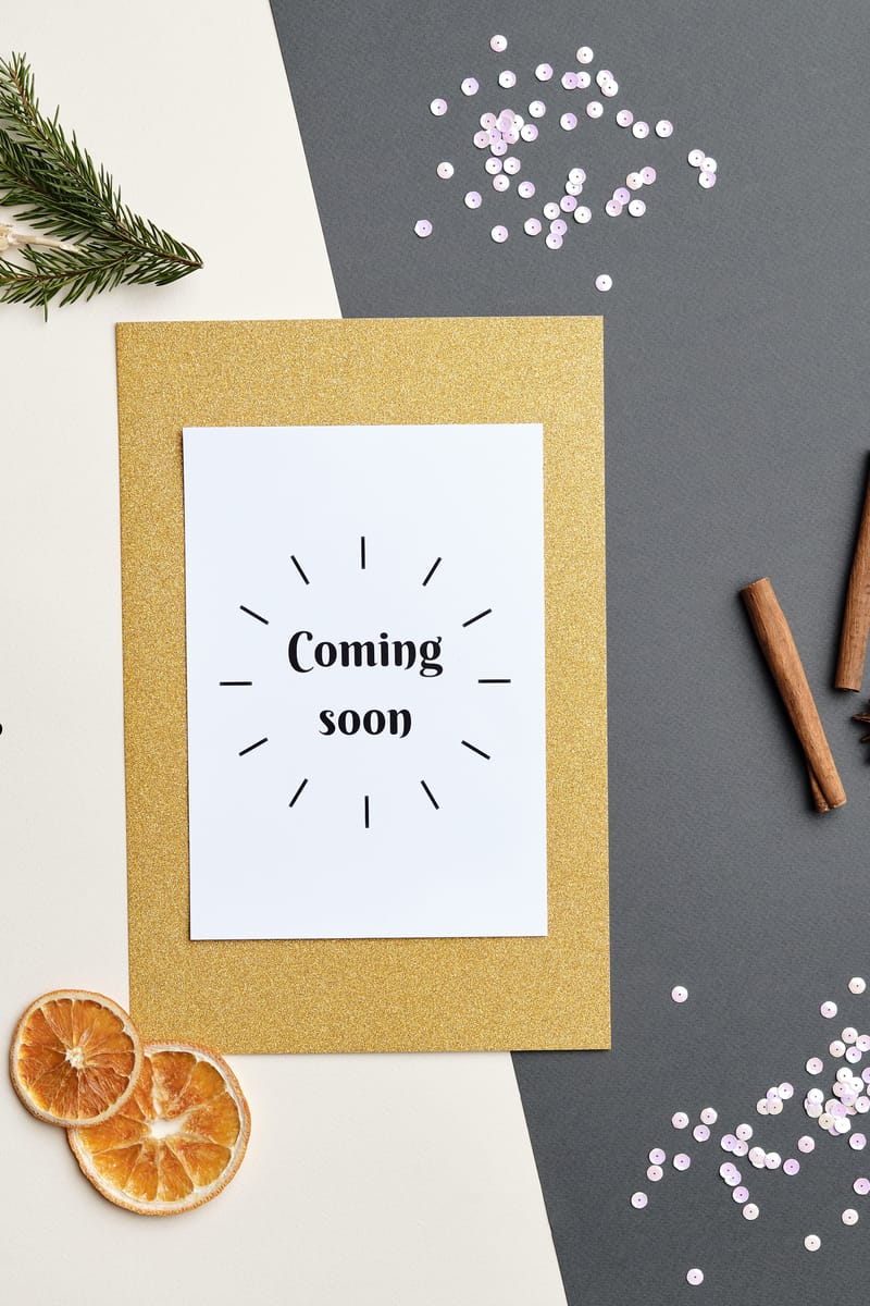 A festive holiday-themed flat lay featuring a 'Coming Soon' greeting card with decorative elements.